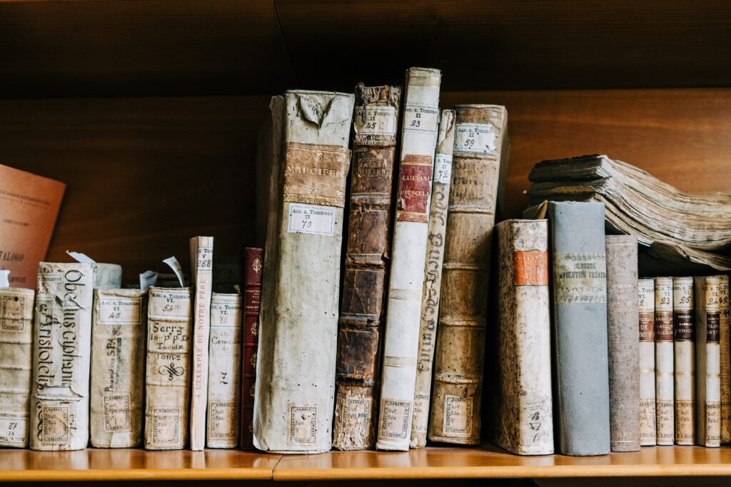 Foto com uma estante cheia de livros antigos, remetendo às expressões latinas. 